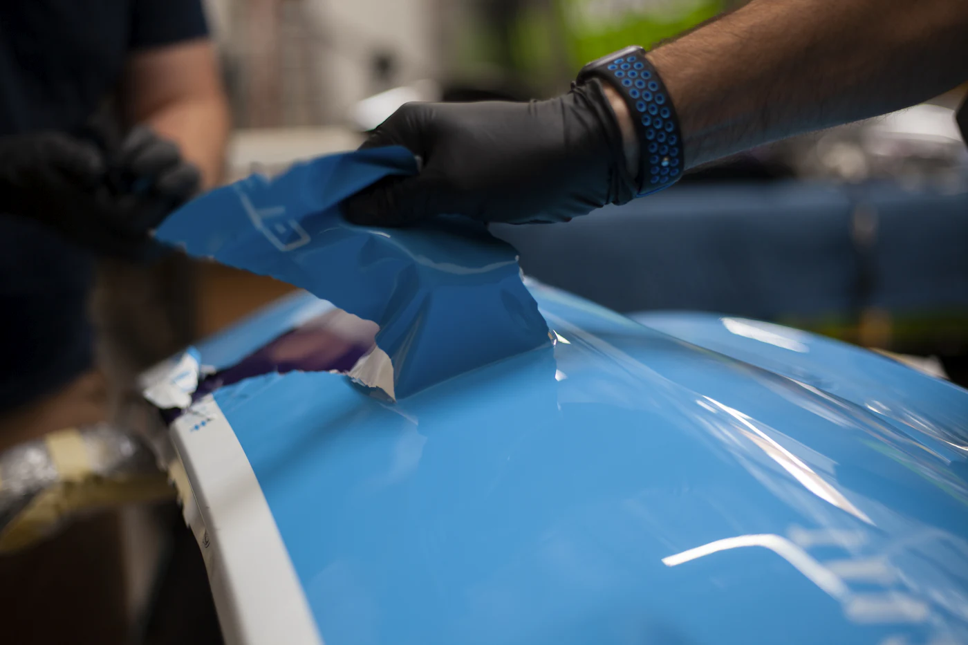Gloved hands finishing the paintwork on a blue car
